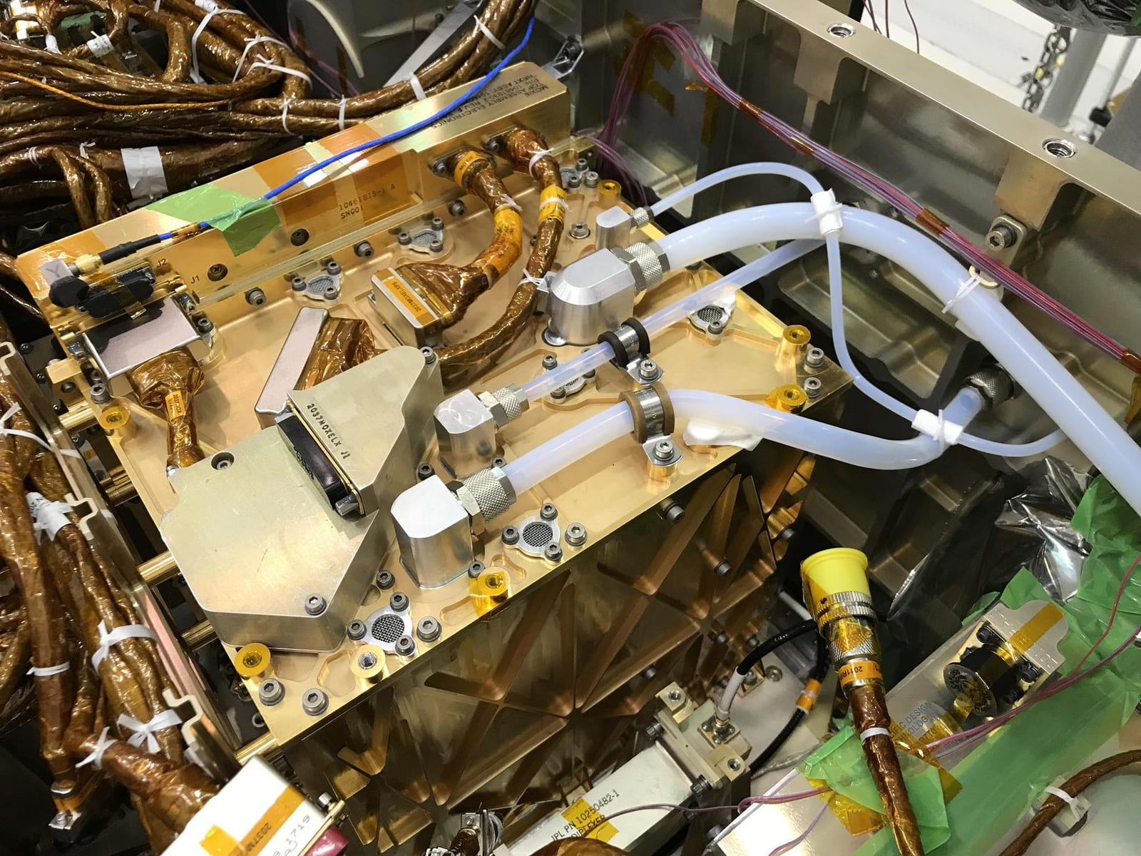 A gold-foil-wrapped instrument box surrounded by cabling and structure inside a rover chassis.