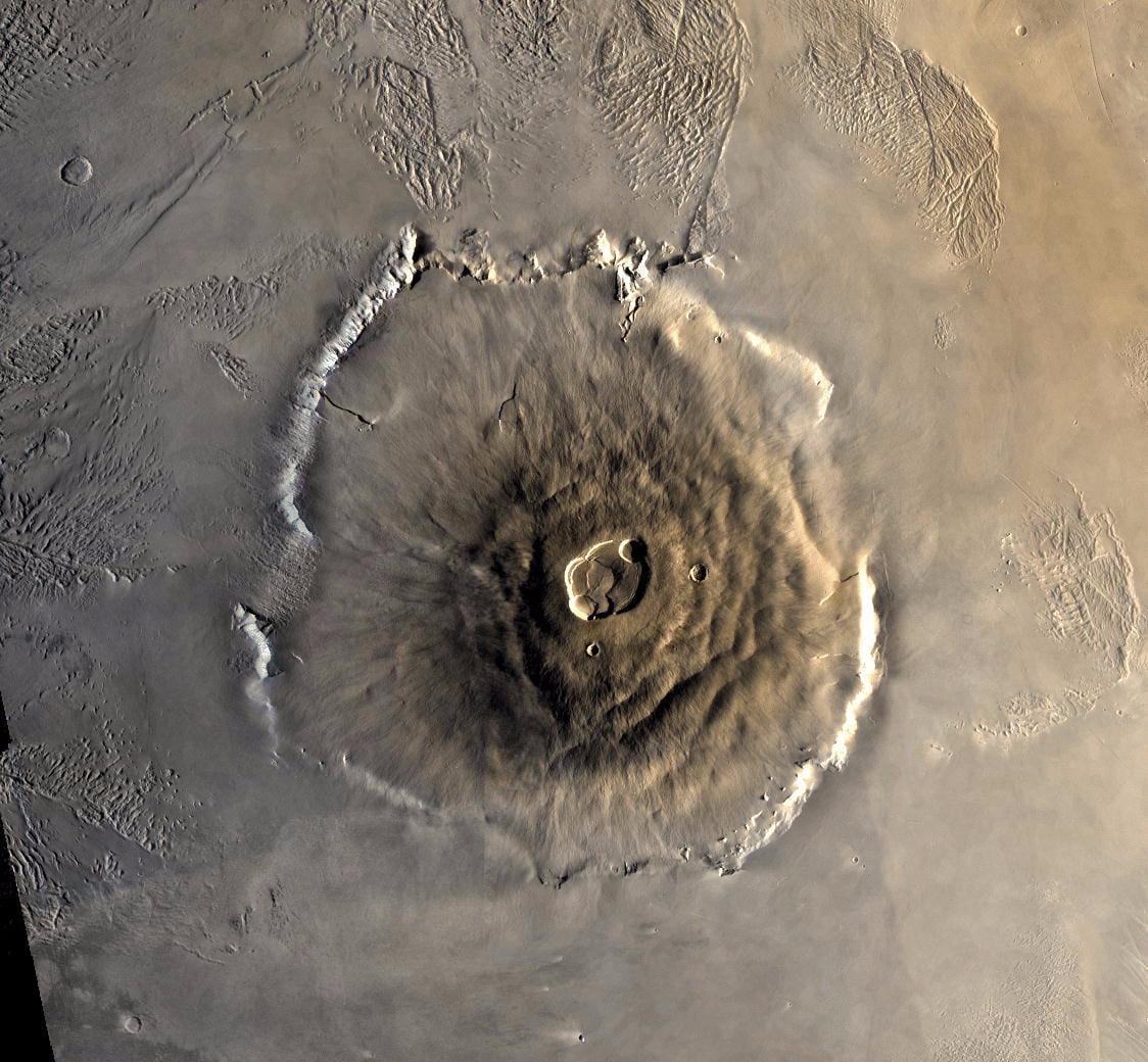 An overhead view of an enormous shield volcano with a complex summit caldera and a steep encircling scarp.